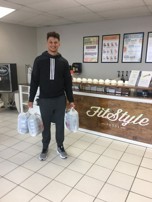 Patrick Mahomes holding three bags full of delicious Fitstyle Foods meals